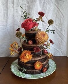 a three tiered cake decorated with flowers on a wooden table next to a white wall