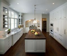 a large kitchen with white cabinets and wood floors