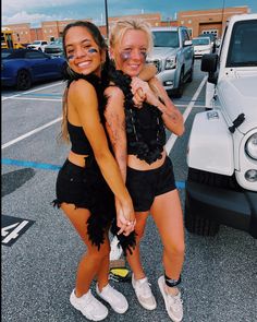 two young women standing next to each other in front of a white truck and holding hands