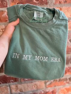 "Embroidered \"in my mom era\"  Unisex fit" Mother's Day Crew Neck Top With Embroidered Text, Mother's Day Embroidered Text Crew Neck Top, Casual T-shirt With Embroidered Text For Mother's Day, Casual Embroidered T-shirt For Mother's Day, Mother's Day Cotton T-shirt With Embroidered Graphics, Mother's Day Embroidered Cotton Sweatshirt, Mother's Day Cotton Top With Embroidered Graphics, Cotton Tops With Letter Embroidery For Mother's Day, Mother's Day Gift Tops With Letter Embroidery