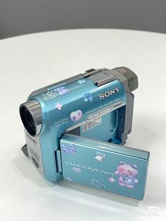 a digital camera sitting on top of a white table next to a small box with an animal sticker on it