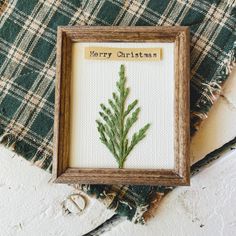 a cross - stitch christmas card with a pine tree in the middle and merry christmas written on it