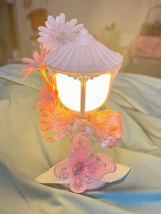 a lamp that is on top of a bed with flowers in the light and butterflies around it