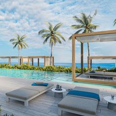 an outdoor swimming pool with chaise lounges next to it and palm trees in the background