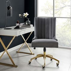 a green velvet office chair with gold legs in front of a white desk and black wall