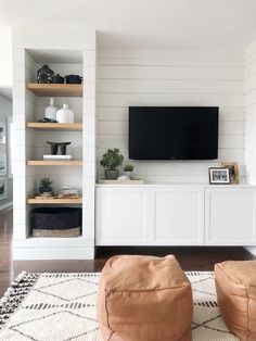 a living room filled with furniture and a flat screen tv on top of a wooden shelf