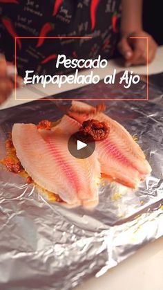 two fish fillets sitting on top of aluminum foil covered in seasoning next to a person