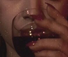 a woman holding a glass of wine up to her face