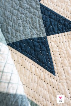 a close up view of a quilt on a bed with blue and white squares in the middle