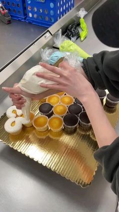 a person reaching for some cupcakes on a tray