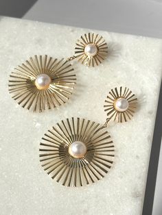 Elevate your style with our striking Sunburst Pearl Earrings! These statement drop earrings feature a lustrous pearl accent and are crafted in elegant gold, adding a touch of sophistication to any outfit. The abstract sunburst shape adds a unique touch to these must-have earrings. Make a bold fashion statement with our Sunburst Pearl Earrings! Elegant Starburst Earrings For Party, Elegant Sunburst Earrings As A Gift, Elegant Gold Starburst Jewelry, Gold Starburst Earrings For Party, Elegant Sun Design Drop Earrings, Elegant Gold Earrings With Sun Design, Gold Starburst Party Earrings, Elegant Gold Sunburst Jewelry, Elegant Sun Design Starburst Jewelry