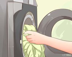 a hand is holding a cloth over the front of a washing machine with it's door open