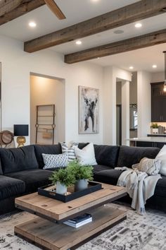 a living room filled with black furniture and lots of wood beamed ceiling beams in the background