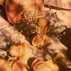 a glass of wine sitting on top of a table next to flowers and a purse