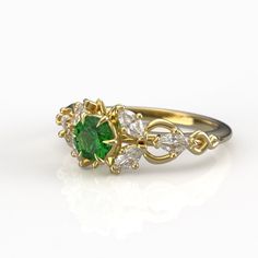 a green and white diamond ring with leaves on it's sides, set in yellow gold