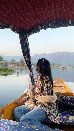 a woman sitting in the back of a yellow boat on top of a body of water