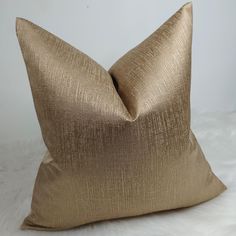 a gold pillow sitting on top of a white furnish