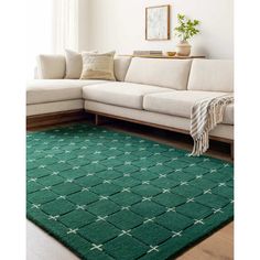 a living room with a green rug on the floor and a white couch in front of it