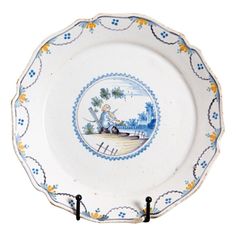 a blue and white plate with an image of a man sitting on a boat in the water