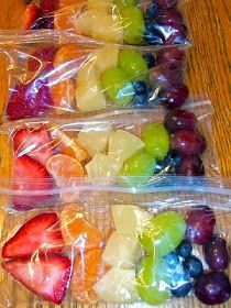 four plastic bags filled with fruit on top of a wooden table