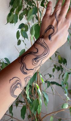 a person's arm with tattoos on it and a tree in the back ground