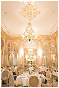 an elegant dining room with chandelier and tables set for dinner in white linens