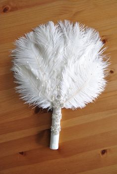 a white feather fan sitting on top of a wooden table