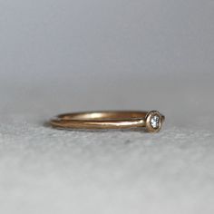 "Modern diamond pebble wedding ring. A sparkly 2.5mm sparkly white diamond is set in a handmade pebble. Wear it alone for an elegant wedding ring, or stack them up for a sparkly statement. Details: *Finish - Comes with a brushed satin finish (pictured) unless you contact me to request a high polish. *Diamond - 2.5mm, conflict-free **Available in 14k rose gold for the same price as 14k yellow gold....If you want rose gold, purchase the 14k yellow and leave me a note in the \"note to seller\" sect Minimalist Diamond Ring With Round Stone, Minimalist Round Diamond Ring, Diamond Stackable Rings With Bezel Setting For Promise, Promise Ring With Single Diamond And White Topaz, Minimalist Diamond Birthstone Ring, Round Cut, Minimalist Round Cut Diamond Birthstone Ring, Diamond White Diamond Ring With Bezel Setting For Promise, Promise Diamond Ring With Bezel Setting In Diamond White, Wedding Diamond Ring With Single Round Stone