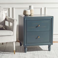 a blue nightstand with two white vases on top of it next to a chair