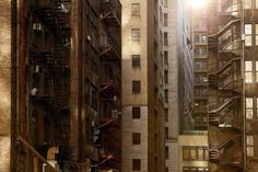 an alleyway in the city with tall buildings and fire escape stairs on either side