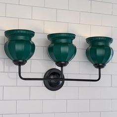 three green lights are on the wall in front of a white brick wall and black pipe