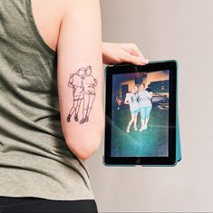 a woman with a tattoo on her arm holding an ipad