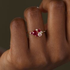 a woman's hand with a red and white diamond ring on her left hand