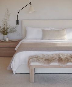 a bedroom with a bed, nightstands and two plants on the side of the bed