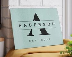 a sign that says anderson est - 2024 sits on a bed in front of a brick wall