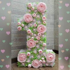 the number one is made out of pink flowers and green leaves on a table in front of a brick wall