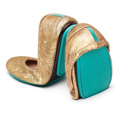 two gold and turquoise shoes are shown on a white background, one is open to show the inside