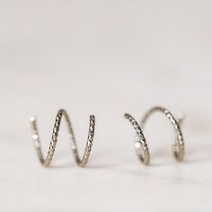 Tiny Double Hoop Earrings, Minimal Spiral Earrings, Tiny Twist Earrings, Double Hoop Earrings, Double Piercing, Diamond Cut Hoop EarringsTwist these little coils in and instantly get the appearance of two lobe piercings.(You only need ONE piercing to make these work-- they give the look of two!)(It can also be worn with two holes in case you have them)All you do is thread one side through your first hoop until the other side sits comfortably on your earlobe giving the illusion of a second hole. Spiral Earrings With A Modern Twist, Spiral Sterling Silver Single Wrap Earring, Sterling Silver Spiral Wrap Earring, Sterling Silver Spiral Single Wrap Earring, Spiral Single Earring For Everyday Wear, Everyday Spiral Single Earring, Silver Spiral Wrap Earrings, Pierced, Adjustable Spiral Metal Hoop Earrings, Modern Twist Silver Hoop Earrings With Ear Wire