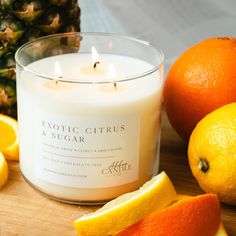 an orange slice next to a candle on a wooden table with other fruit around it