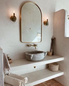 a bathroom with a sink, mirror and towels on the shelf in front of it