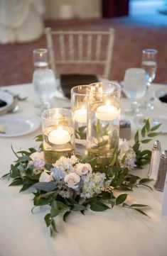 candles are lit on top of the centerpieces at this wedding dinner table setting