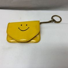 a yellow bag with a smiley face on the front and a key chain attached to it