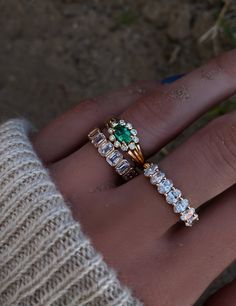 a person's hand with a ring on top of it and an emerald in the middle