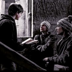 three people sitting down and one is holding a book