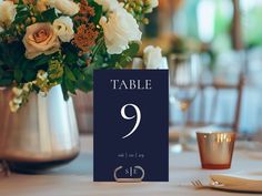 a table number with flowers in a vase on top of the table at a wedding reception