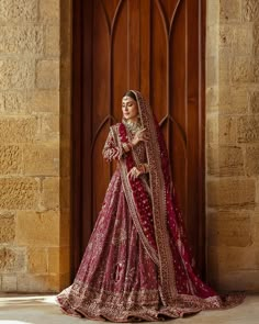 a woman in a red and gold bridal gown standing by a door with her hands on her hips