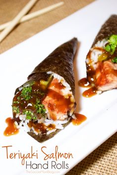 two pieces of sushi on a white plate with sauce and broccoli in the center