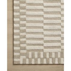 a white rug on top of a wooden floor next to a wall with an abstract design