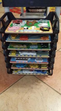 a stack of children's books sitting on top of a black cart with wheels