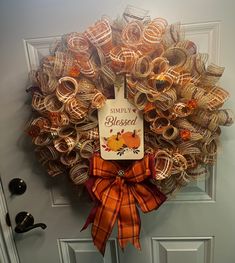 a wreath is hanging on the front door with an orange ribbon and a happy thanksgiving sign